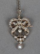 An Art Nouveau diamond and pearl drop gold backed pendant brooch
Of scrolling organic form,