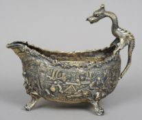 A large unmarked gilt white metal sauceboat
The body decorated with allegorical scenes and a