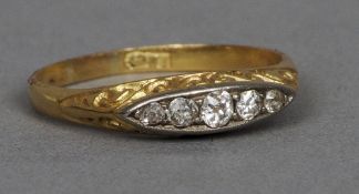 An 18 ct gold five stone diamond ring
The navette set stones above the scrolling pierced shoulders.