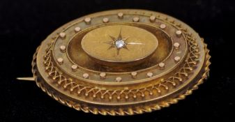 A Victorian 15 ct gold target brooch
The front centred with a diamond, the reverse with a glazed