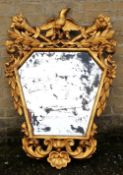 An 18th century style carved giltwood mirror
Of pierced floral form, the top carved with a bird