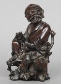 A Japanese carved wood figure of a seated sage
A mythical beast at his feet, both with glass inset