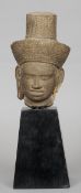 A carved stone male head, Khmer, possibly 10th century
Mounted on an ebonised plinth base.  The head