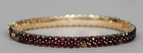 A 19th century unmarked gold garnet set bracelet
Of hinged bangle form, set with with two rows of