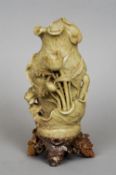 A Chinese carved hardstone group
Worked as flora amongst cabbage leaves, standing on a soapstone