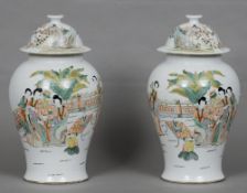 A pair of Chinese porcelain baluster vases and covers
Each decorated with figures in a fenced garden