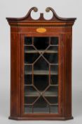 A 19th century inlaid mahogany corner cabinet
The broken swan-neck pediment above a patera inlaid