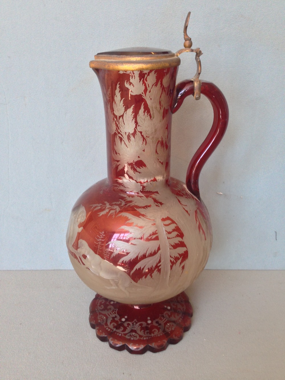 A 19th century Bohemian ruby overlay cut glass ewer
The gilt metal mounted hinged lid with a shell