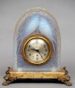 An early 20th century Lalique style opalescent pressed glass mantel clock
The domed case with two