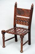 An Arts & Crafts nursing chair
The double panelled carved back above the leather strapwork seat,