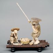 A Japanese carved ivory and hardwood okimono
Formed as figures fishing on a raft, mounted with a