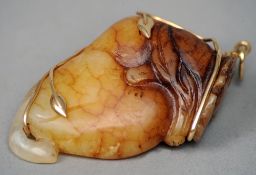 A gold mounted carved russet jade pendant
The gold frame work of leaf form.  5 cms wide.   CONDITION
