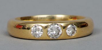 An 18 ct gold and three stone diamond band
The stones gypsy set.   CONDITION REPORTS:  Overall good,