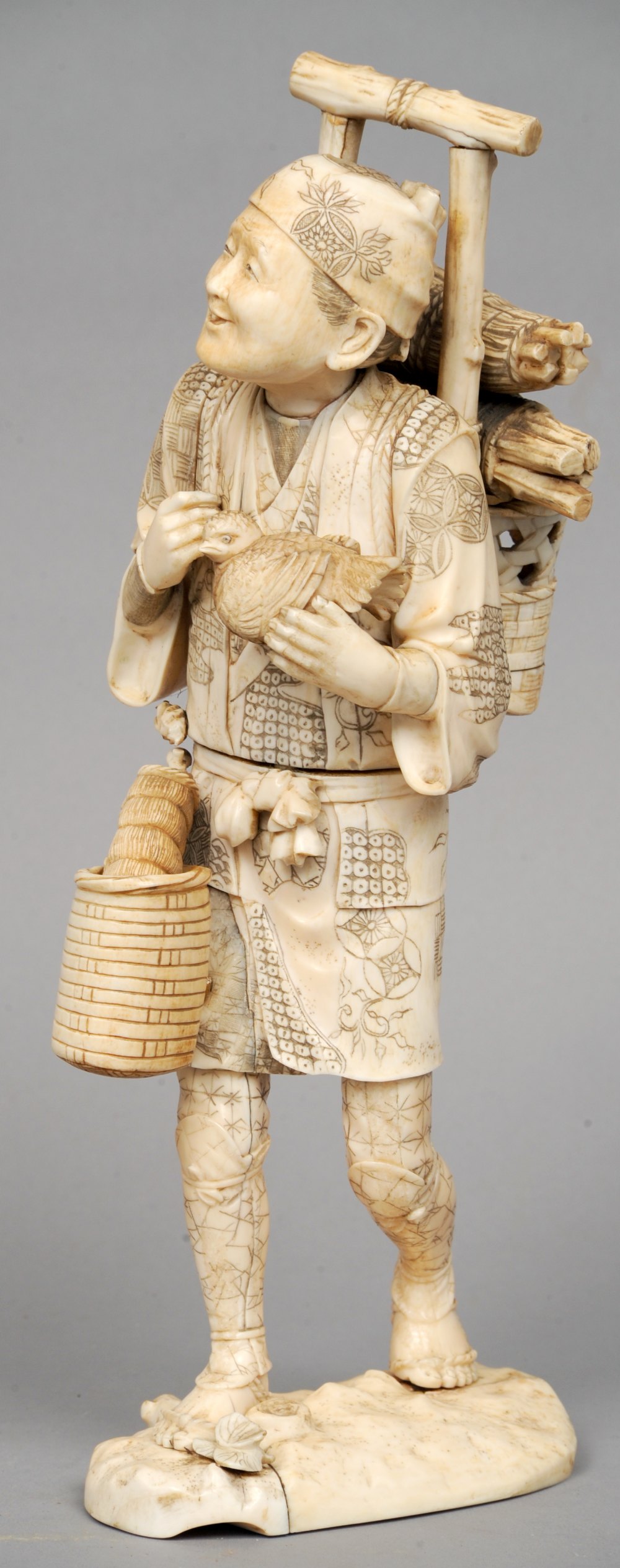 A large 19th century Japanese ivory okimono
Formed as a woodsman, modelled carrying bundles of
