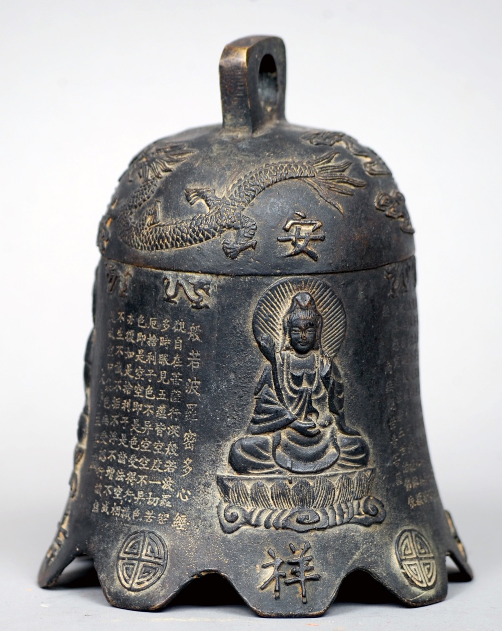 A Tibetan patinated bronze temple bell
Of typical form, decorated with three different scenes of