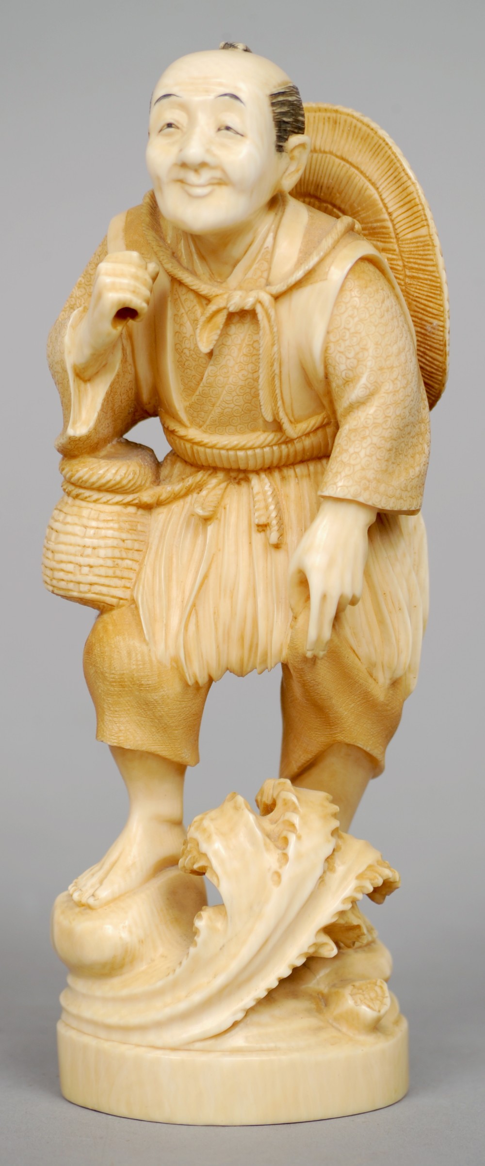 A 19th century Japanese carved ivory okimono
Formed as a gentleman wading with a straw hat over