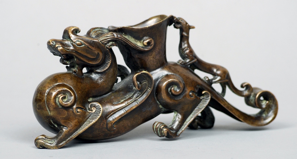 A Chinese bronze group
Modelled as a dragon with an open vessel and further smaller dragon on his