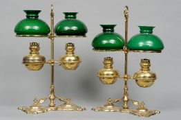 A pair of brass oil lamps
Each with twin adjustable reservoir and twin green glass shades, on an