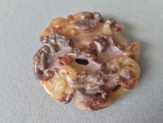 An intricately carved brown and russet jade disc shaped pendant 
Carved with mythical beasts.  6 cms