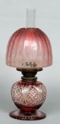 A Victorian ruby overlay cut glass oil lamp
With an etched domed cranberry shade and clear glass