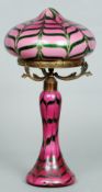 An Art Nouveau glass table lamp
The pink ground with bands of green decoration, the domed shade