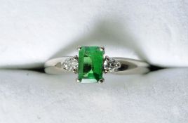 An 18 ct white gold, emerald and diamond ring
The central core set emerald flanked by two small