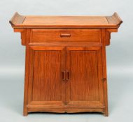 A Chinese hardwood side cabinet
The shaped rectangular top above a frieze drawer and twin cupboard
