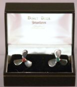 A pair of silver cufflinks
Modelled as ships propellers, hardstone set as Port and Starboard, in