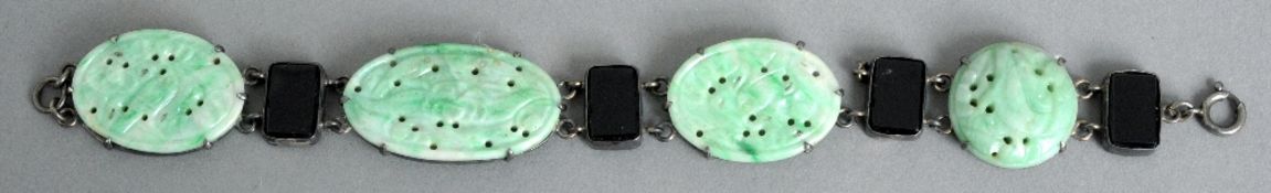 An Art Deco style unmarked white metal mounted jade bracelet
Each roundel of pierced and carved