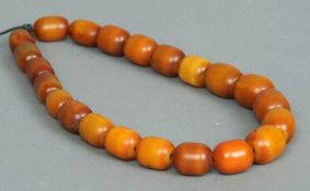 An amber bead necklace
Each orange bead of oval form.  The largest 2.75 cms wide.   CONDITION