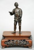 A Meiji period Japanese bronze figure
Formed as a gentleman holding a purse, mounted on a pierced