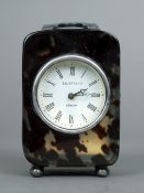 A small tortoiseshell carriage clock
With unmarked silver loop handle and bun feet, the circular