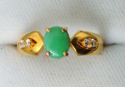 A jade and diamond ring
The shank marked 23 carat, the central cabochon jade stone flanked by twin