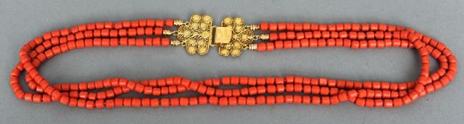 A three strand coral necklace
Mounted with a 14 ct gold filigree clasp; together with an amber