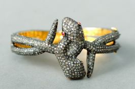 An unmarked diamond encrusted bangle form bracelet
Formed as entwined snakes with ruby set eyes.