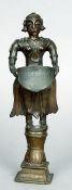 A 19th century Indian bronze figure
Standing in typical attire holding a scoop, mounted on a