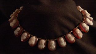 A Continental unmarked yellow metal necklace Comprising twenty-four hand carved agate set cameo
