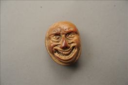 A 19th century carved coquilla nut box The removable lid carved with a menacing face. 4 cms wide.