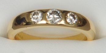 An 18 ct gold three stone diamond ring The plain band gypsy set. General wear, ring size O/P,