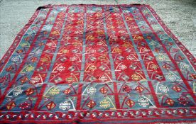 A kilim carpet The red central field with repeating tree and honeycomb design within similar