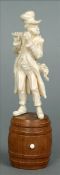 A 19th century Dieppe carved ivory figure Modelled as a flutist, standing on a turned wooden barrel.