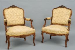 A pair of 19th century French walnut open armchairs The scrolling florally carved serpentine top
