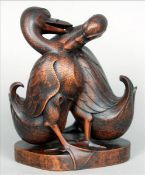 A pair of carved hardwood models of ducks Modelled fighting, standing on a plinth base. 22 cms high.