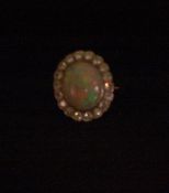 An 18 ct gold opal and diamond cluster ring The central cabochon opal encircled by nineteen
