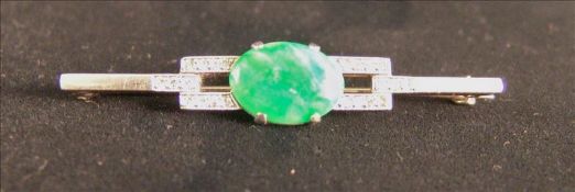 An unmarked white metal apple green jade and diamond bar brooch The central oval stone encircled