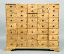 A 19th century painted pine bank of drawers Comprising forty small drawers, each with turned painted