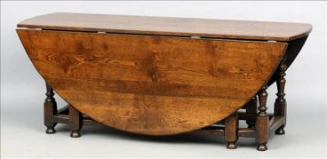 An 18th century style oak double gate-leg drop leaf dining table The oval twin flap top above a