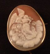 A 9 ct gold mounted cameo brooch Carved with Eros wooing a maiden surrounded by roses and clouds.