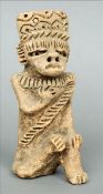 A terracotta figure, possibly South American Modelled seated, wearing a headdress with geometric