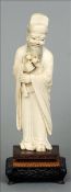 A 19th century Chinese carved ivory figure Formed as a bearded gentleman in flowing robes holding